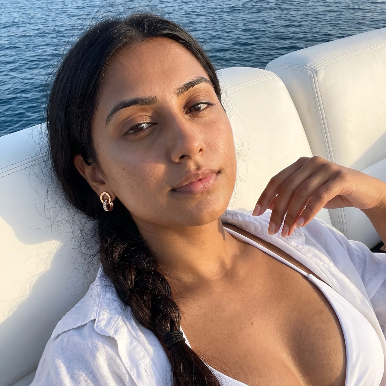 Woman on a yacht wearing the rose gold huggie hoop earrings | SKU: 11137578-rose-gold