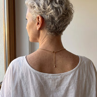 Thumbnail for Back of the neck of a grey-haired woman showing the clasp and extension chain of the gold clover photo necklace | SKU: TPH-CLVN-GOLD