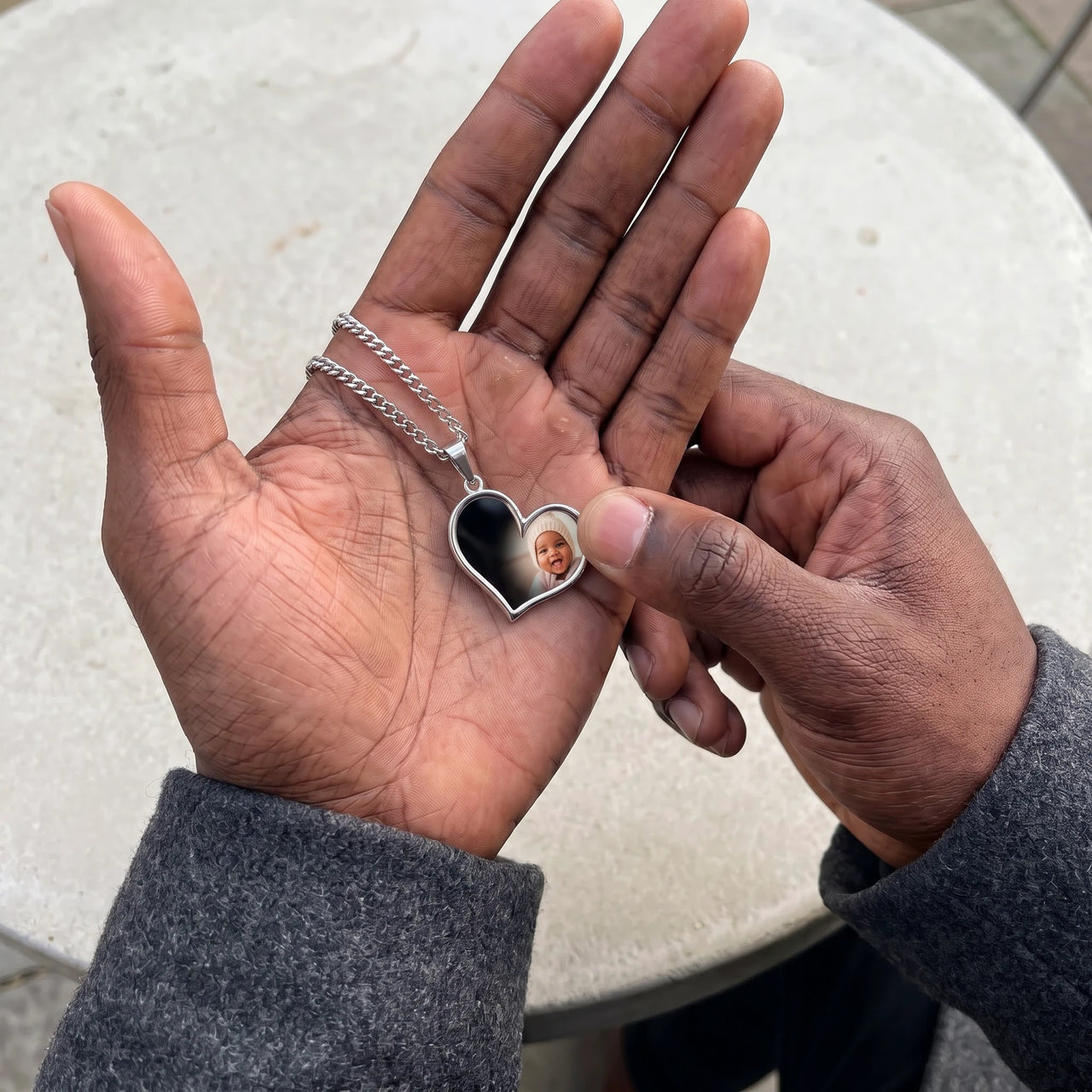 Thumb warming the silver heart pendant: the hidden photo appears under the thumb while the rest stays black | SKU: TPH-HRTN-SILVER